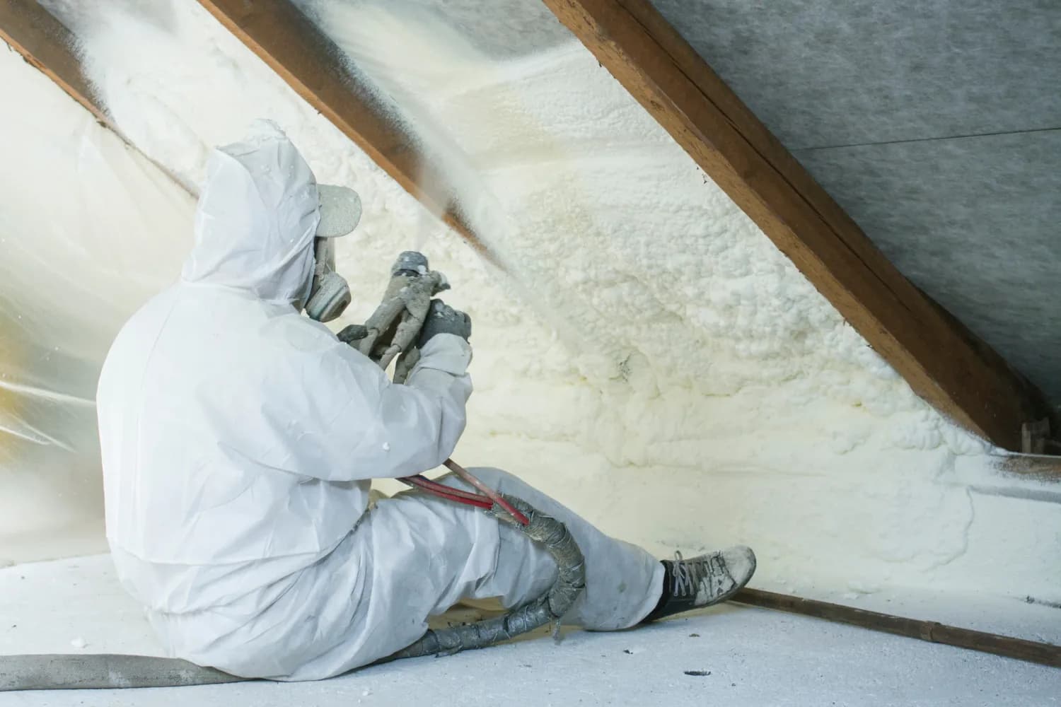 Technician spray-foaming the underside of an attic roofline